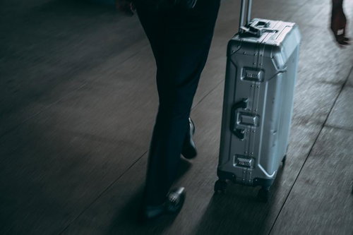 空港でスーツケースを運ぶ旅行者の足元と荷物