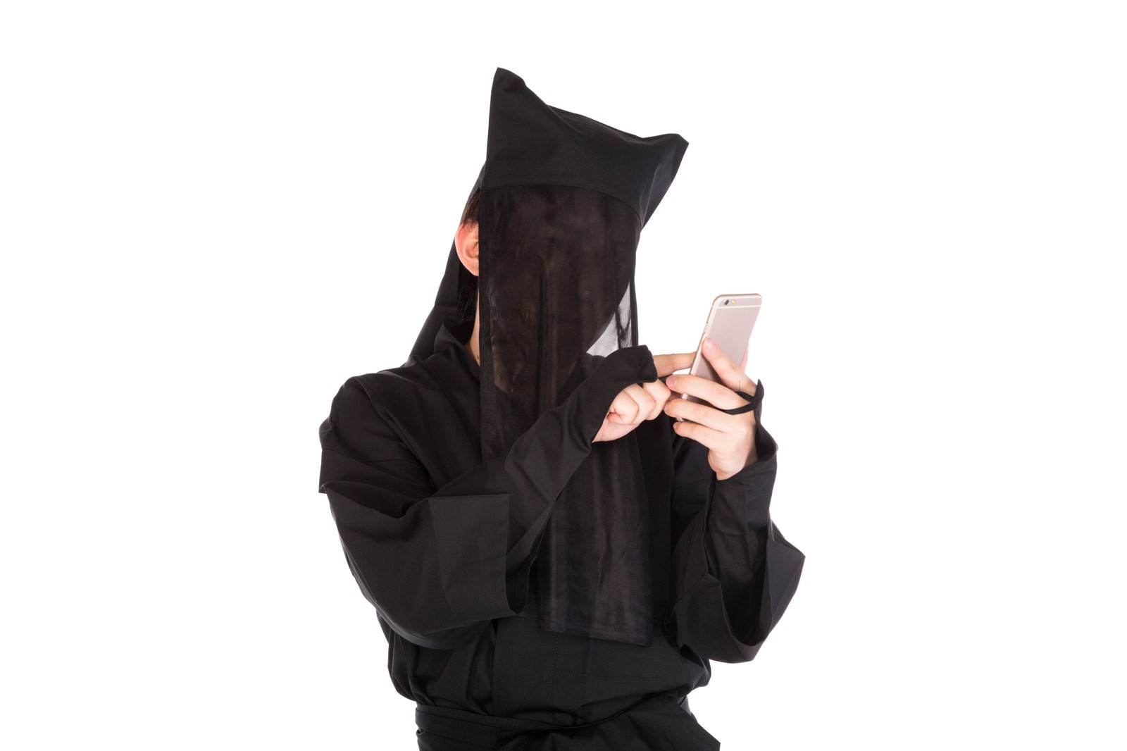 顔を黒いパーカーで覆った人物がシルバー色のスマートフォンを両手で操作している姿［モデル：鈴木秀］