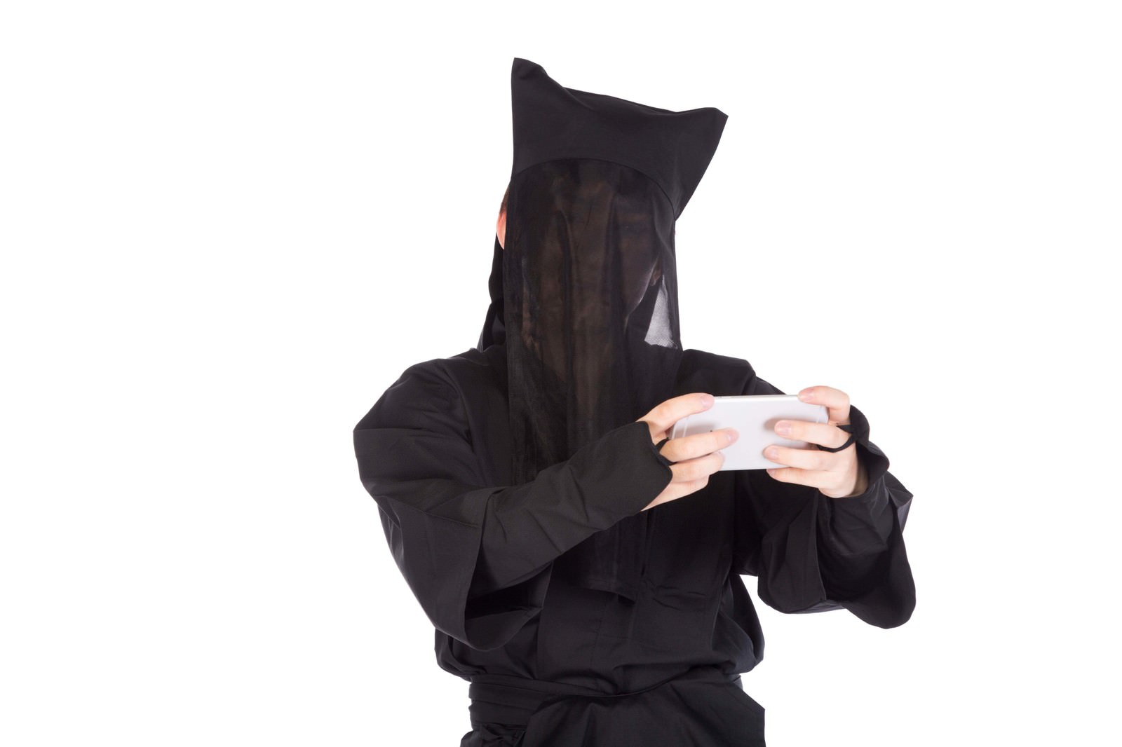 黒いフードと黒いメッシュで顔を隠した人物が白いスマートフォンを両手で持ちゲーム操作をしている［モデル：鈴木秀］