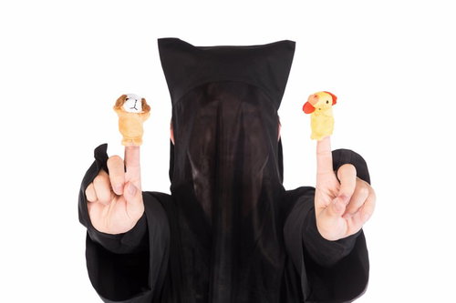 黒子姿で酉と戌の指人形を操る様子、舞台演技の小道具