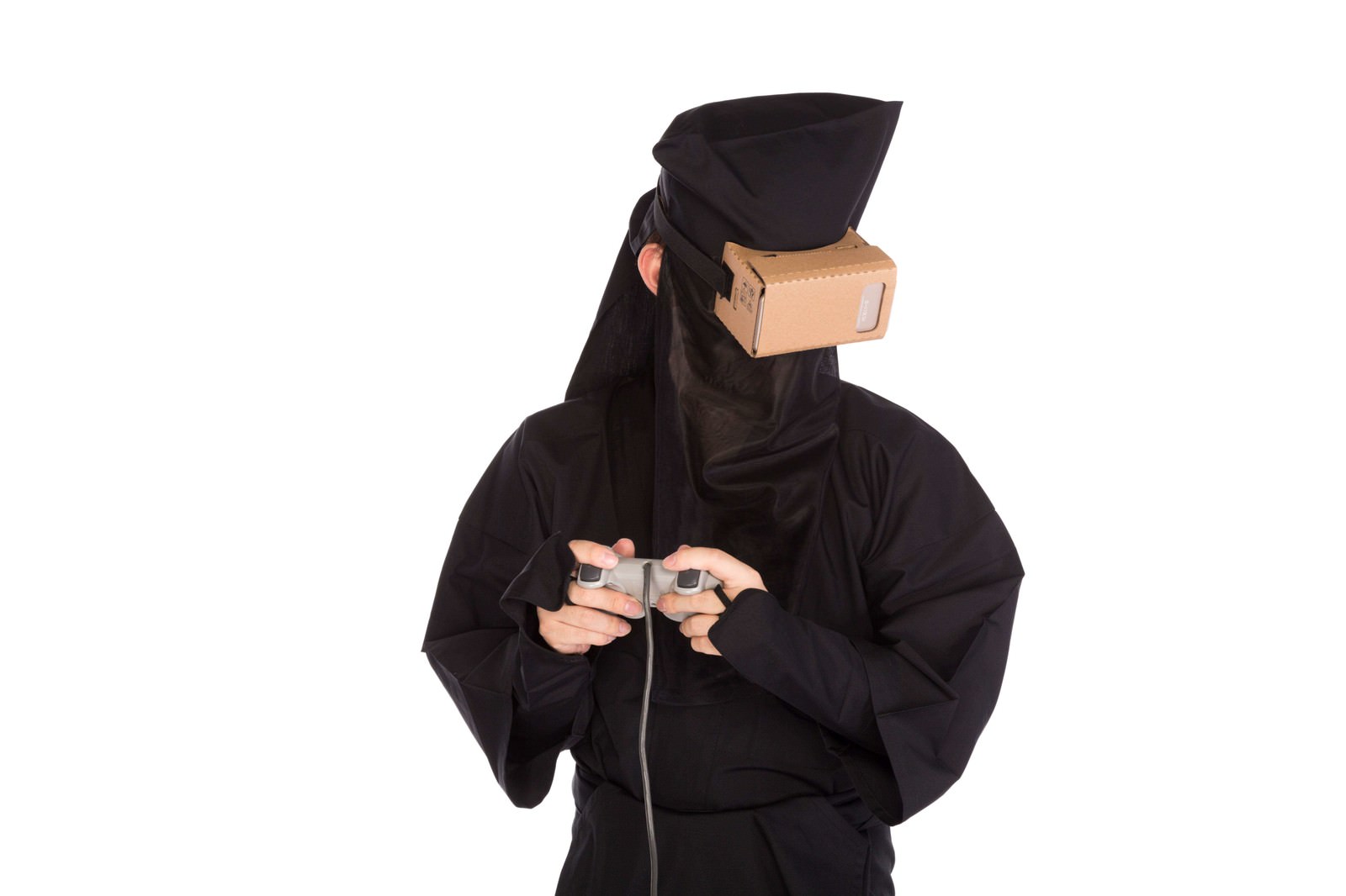 段ボール製VRゴーグルを装着し、黒い衣装を着た人物が両手にゲームコントローラーを持ち、横に顔を向けている［モデル：鈴木秀］