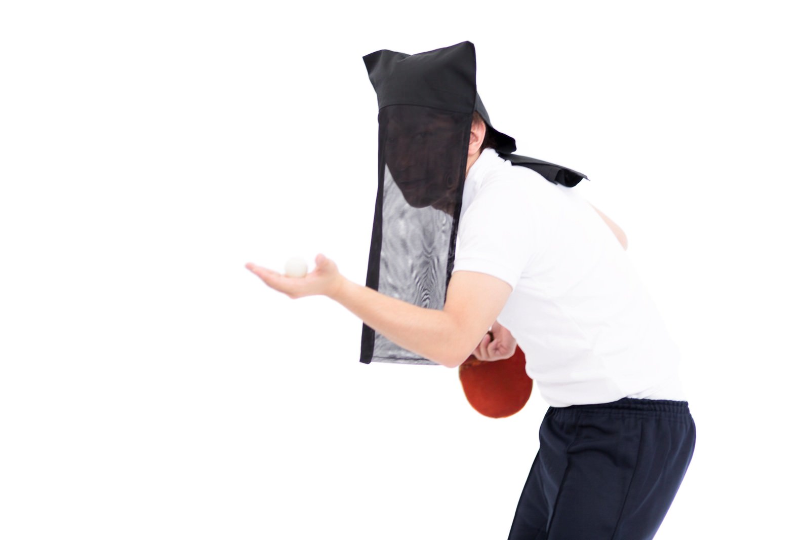 黒いフード付き衣装で顔を隠し、赤いラケットを持ってサーブポーズを取る卓球選手の男性［モデル：鈴木秀］