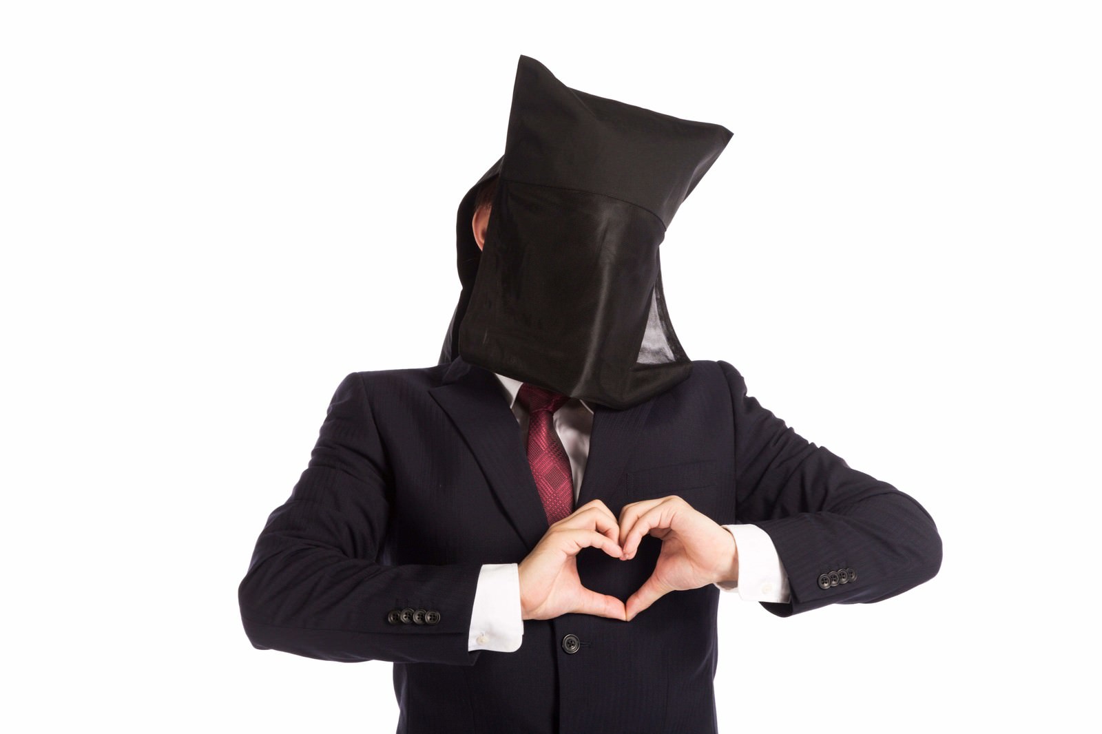 顔を黒い布で覆ったスーツ姿の男性が両手でハート型を形成する［モデル：鈴木秀］
