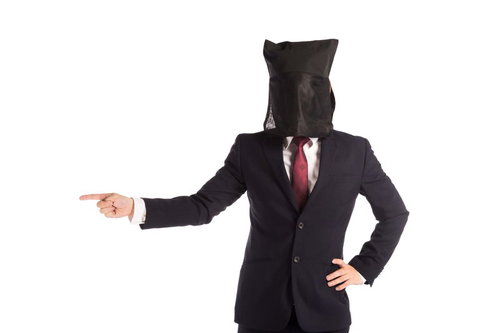 黒い袋をかぶって指をさす黒子スタイルのビジネスマン