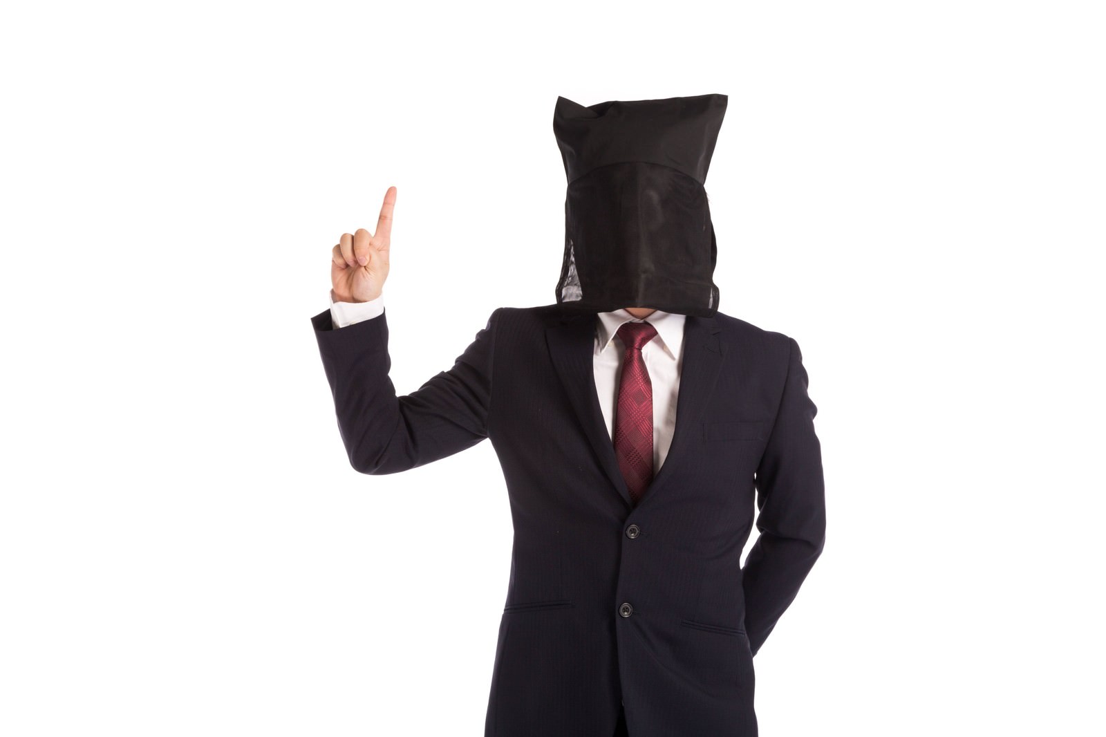 Suited man with black paper bag over head working on laptop at desk