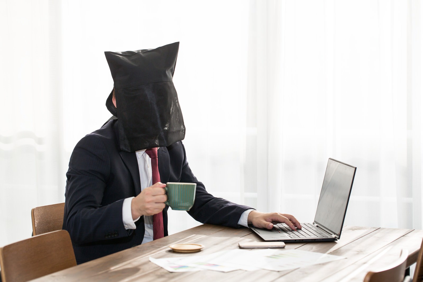 黒いビニール袋を頭から被ってカフェで作業する男性［モデル：鈴木秀］