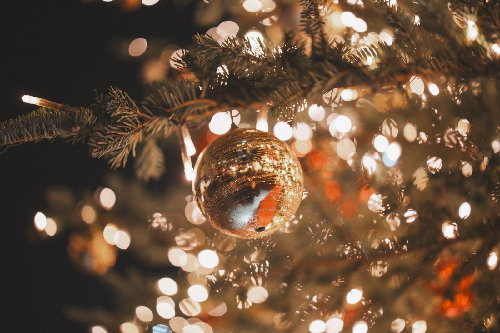 Gold Christmas ornament ball on tree with glowing bokeh lights