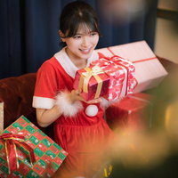 赤いサンタ衣装でクリスマスプレゼントを用意した女性の写真