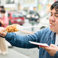 伸びるチーズを楽しむチーズドッグを食べる男性の写真