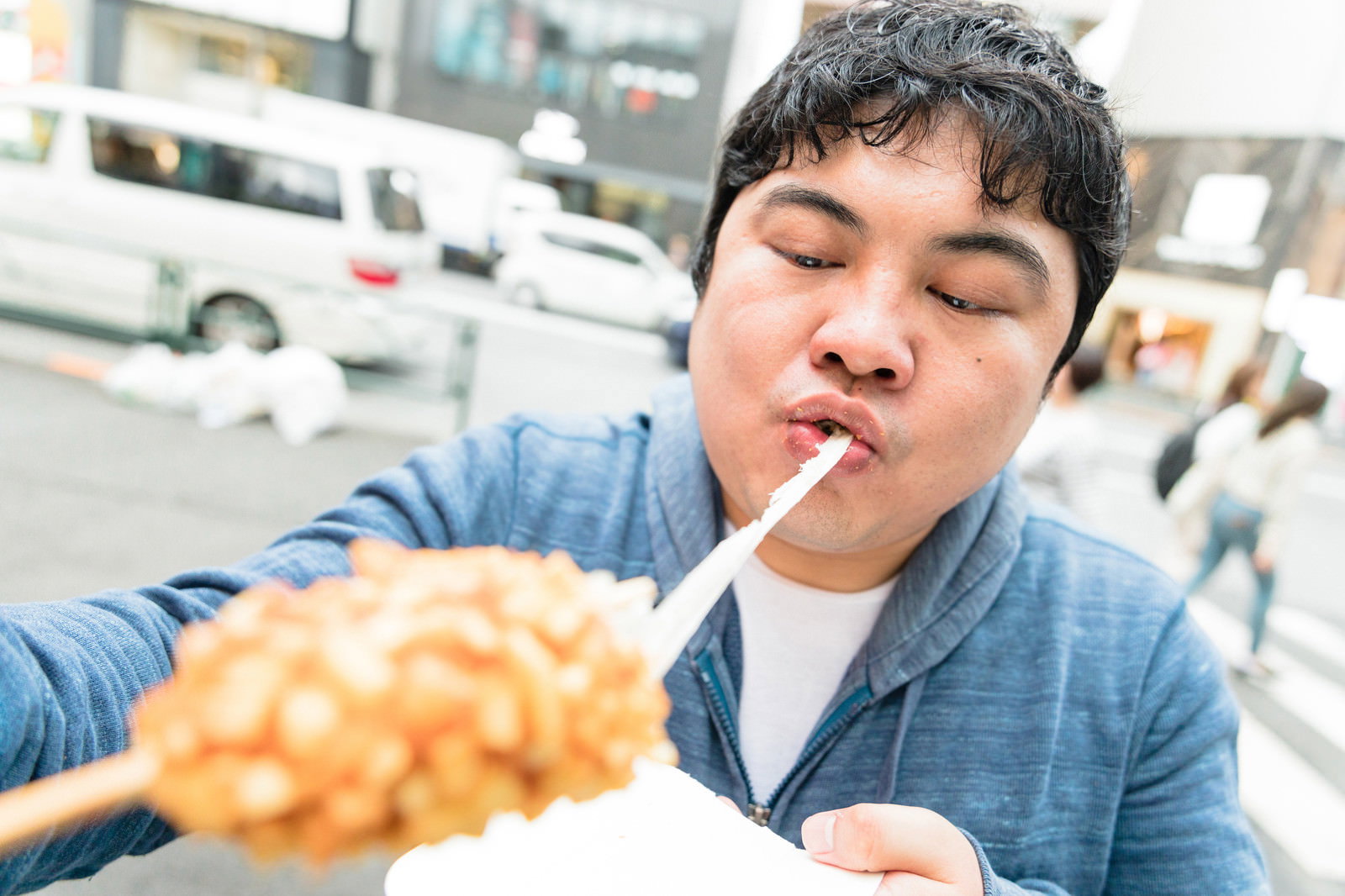 チーズドッグを大きく口を開けて頬張る男性の表情［モデル：段田隼人］