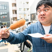 チーズめっちゃ伸びるチーズドッグを頬張る男性の写真