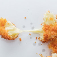 揚げたてのチーズドッグから長く伸びるとろけたチーズの写真