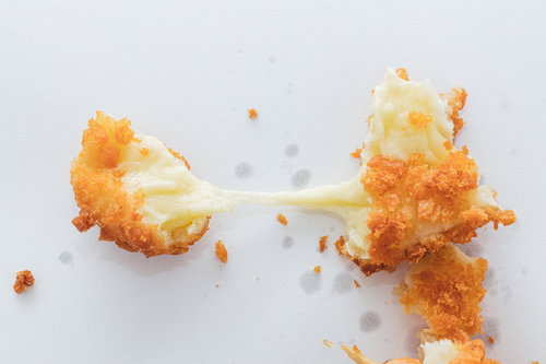 揚げたてのチーズドッグから長く伸びるとろけたチーズ