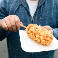 揚げたてのチーズドッグを手持ちする男性の写真