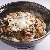 チーズが溶けた高カロリー牛丼、こんがり焼けたチーズと牛肉の丼物の写真