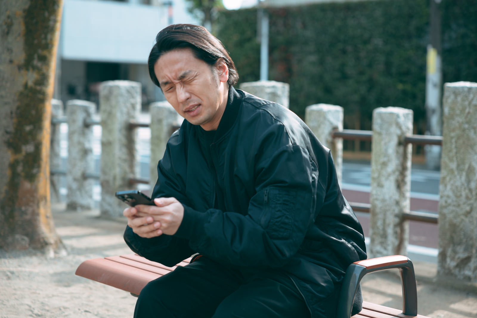 公園のベンチでスマートフォンを操作するアラフォー男性［モデル：大川竜弥］