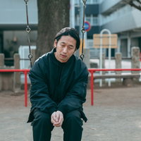 リストラされて公園のブランコで項垂れるアラフォー男性の写真