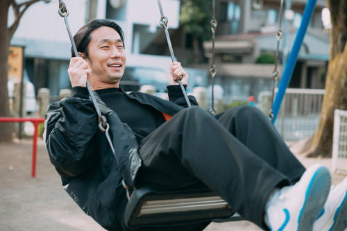 フリー素材モデル10年選手の男性がブランコで笑顔