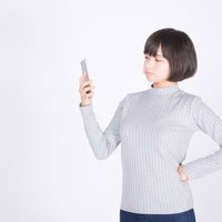 値引き交渉に呆れ顔のスマホ女子、スマートフォンを持ち憤慨する女性の写真