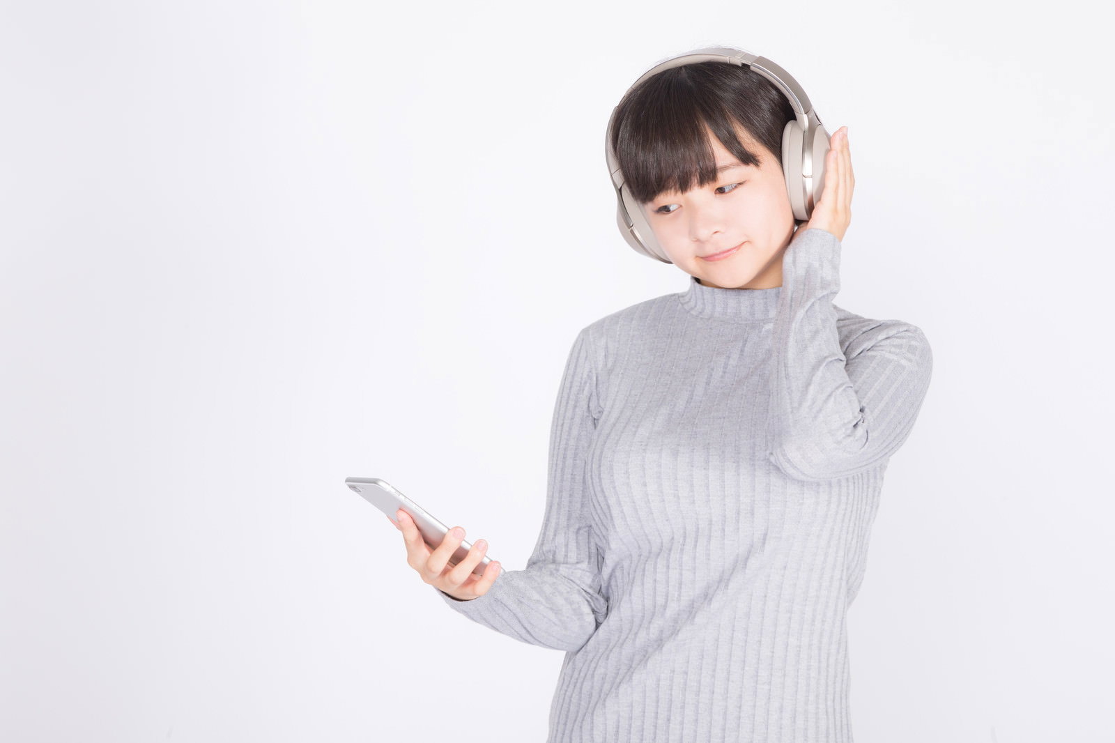 ワイヤレスヘッドホンをつけてスマートフォンを持ち音楽を楽しむ女性［モデル：千歳］