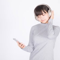 ワイヤレスヘッドホンでスマートフォンの音楽を楽しむ若い女性の写真