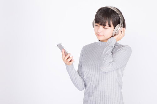 ワイヤレスヘッドホンでスマホの音楽を楽しむ女性