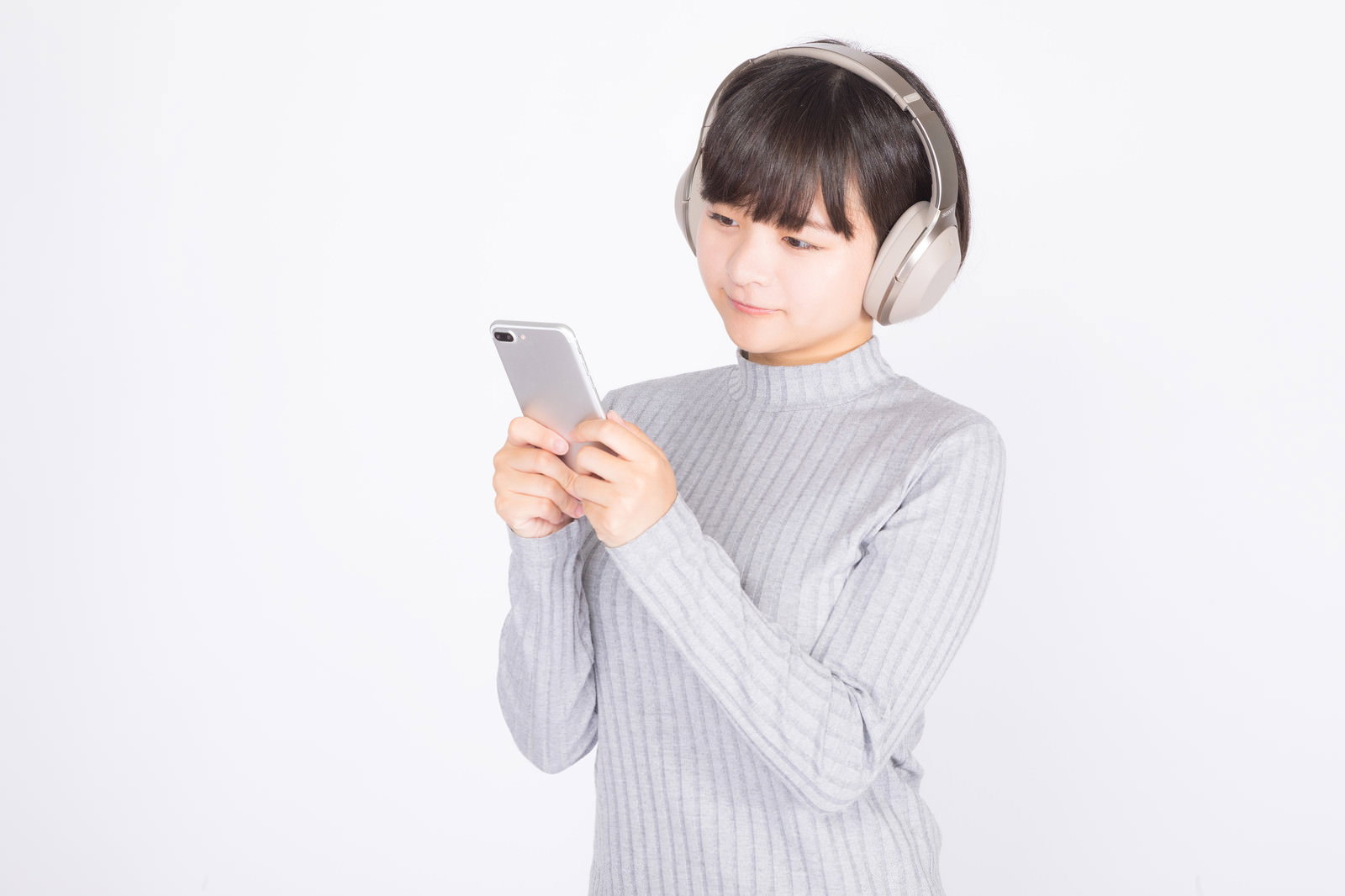 ヘッドホンをつけてスマートフォンで音楽を聴く女性［モデル：千歳］