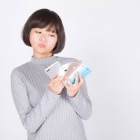 複数台のスマートフォンを使い分ける女性のスマホ比較検討の写真