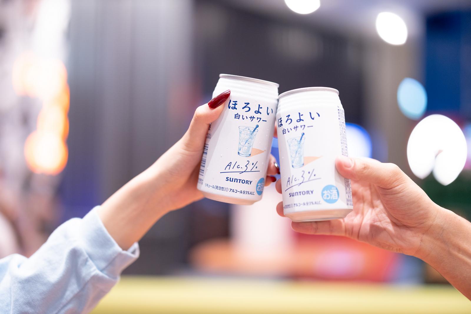 夜の街を背景に缶のお酒で乾杯するカップルの手