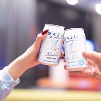 夜景の中で缶のお酒で乾杯するカップルの夜間デートの写真