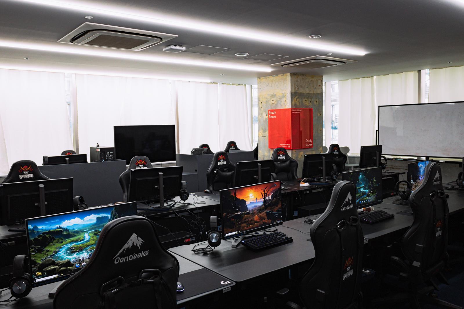 黒いゲーミングチェアとモニターが並ぶeスポーツ用フロアの全景