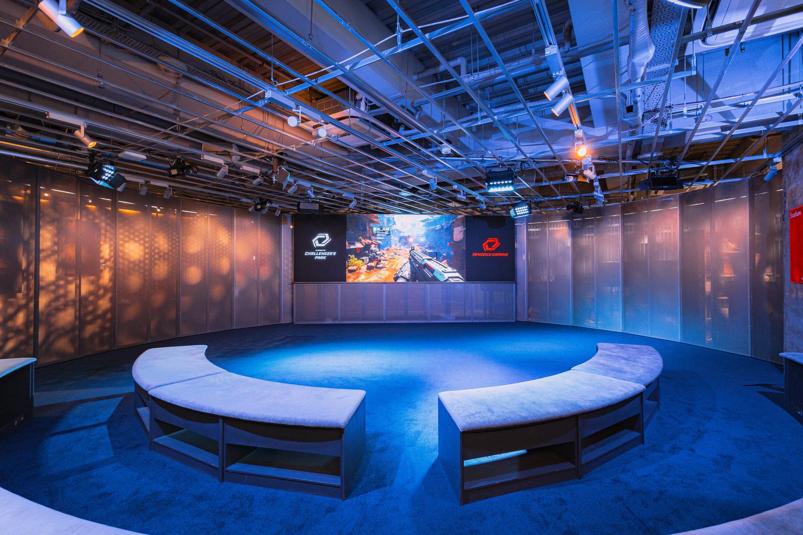 青白いLED照明で照らされたeスポーツスタジアムの会場内。大型モニターと観客席が見える