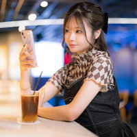 カフェでドリンクを片手にスマホを操作する彼女の写真