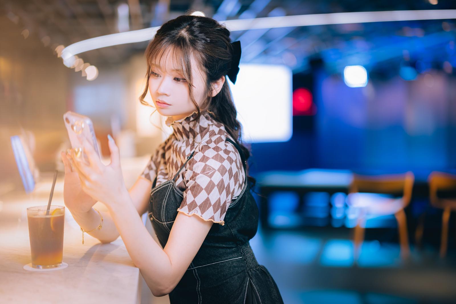 カフェでスマホを持ってコメント返信する女性［モデル：れいか氏］