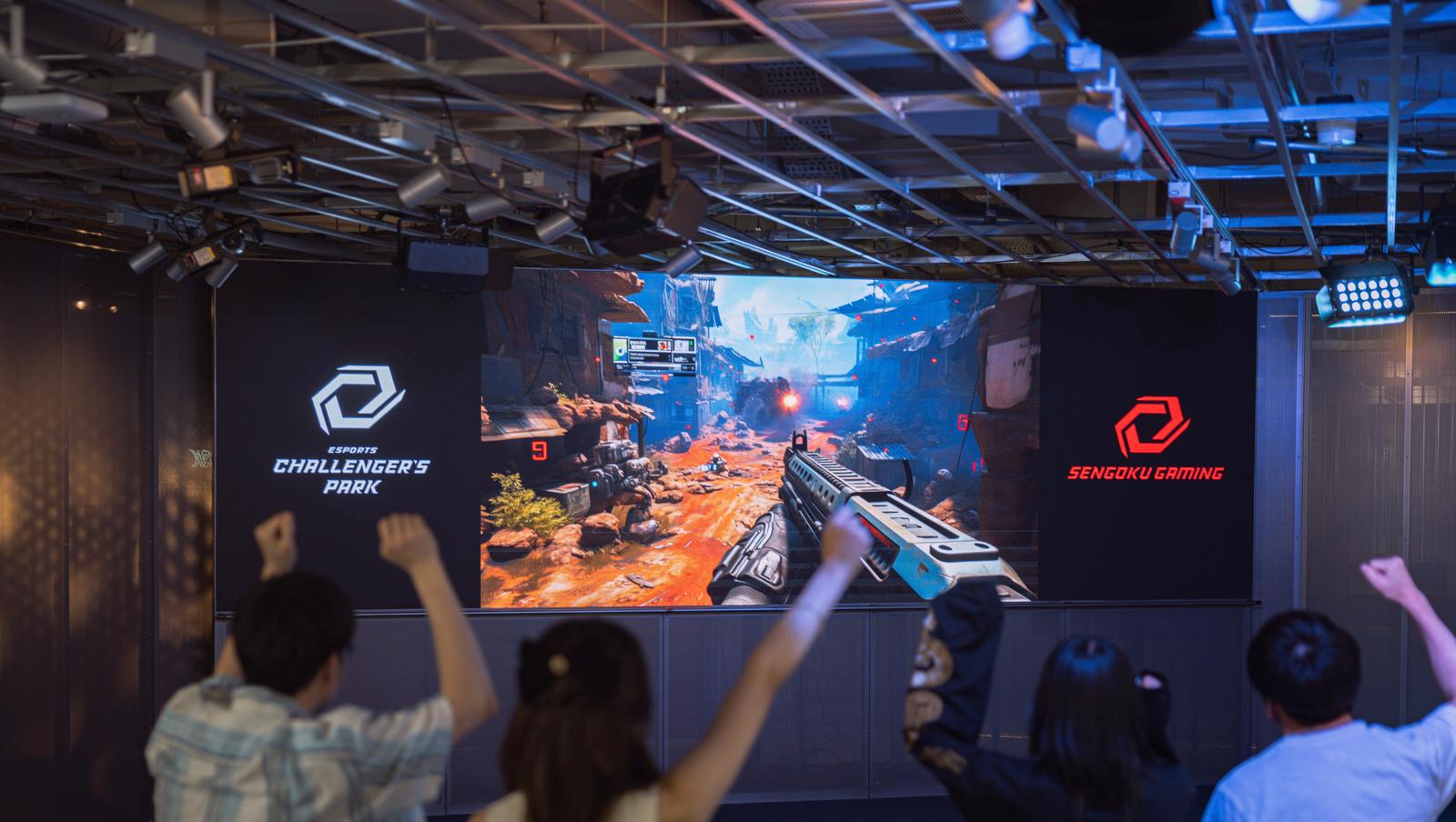 パブリックビューイング会場で大画面のeスポーツゲーム試合を観戦する複数の観客