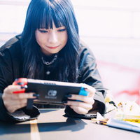 くつろぎながら携帯ゲームに熱中する女性の写真