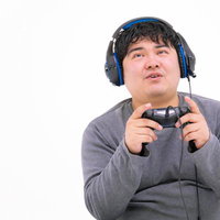 ゲームパッドを握ってPCゲームをプレイする男性の写真