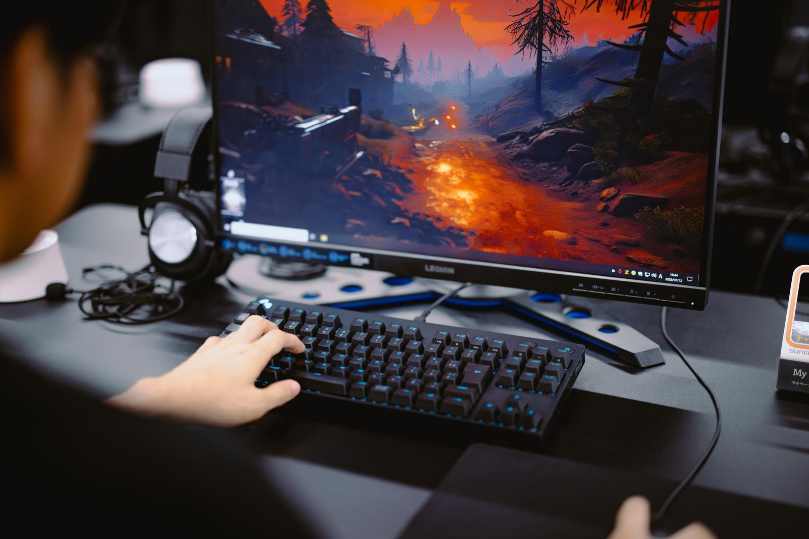 ゲーミングキーボードを持ってFPSゲームをプレイするプロゲーマーがディスプレイを見つめている
