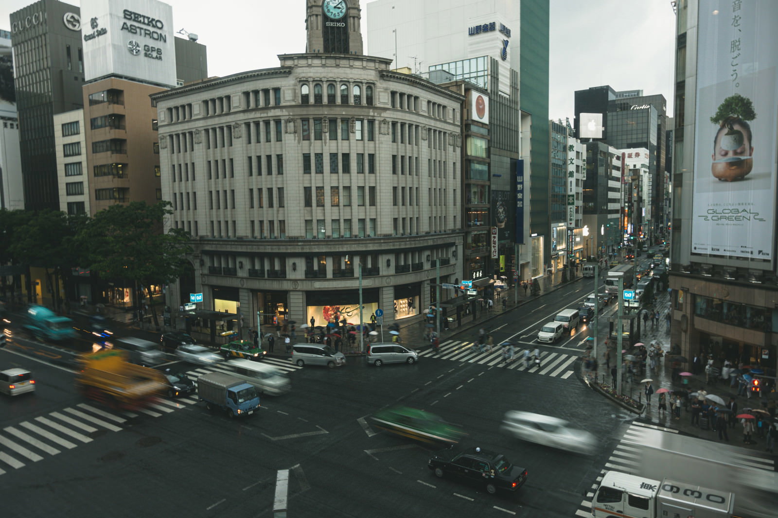 雨に濡れた銀座の交差点と和光の時計塔、車や歩行者が行き交う夜景