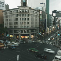 雨に濡れた銀座の交差点に立つ和光の時計塔の写真