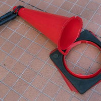 倒れて折れてしまった赤い交通コーンと台座の写真