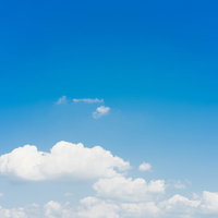 澄み渡った青空に浮かぶ白い雲と積雲のグラデーション風景の写真