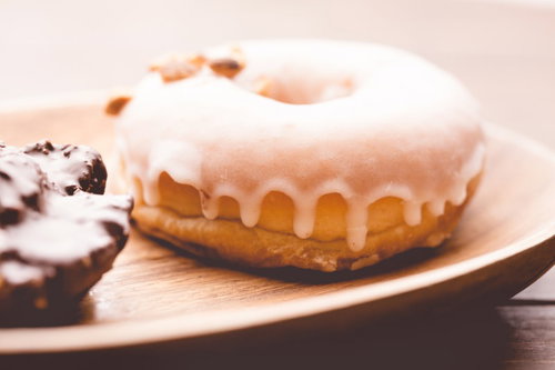 木の皿に載せた白いアイシングのドーナツ