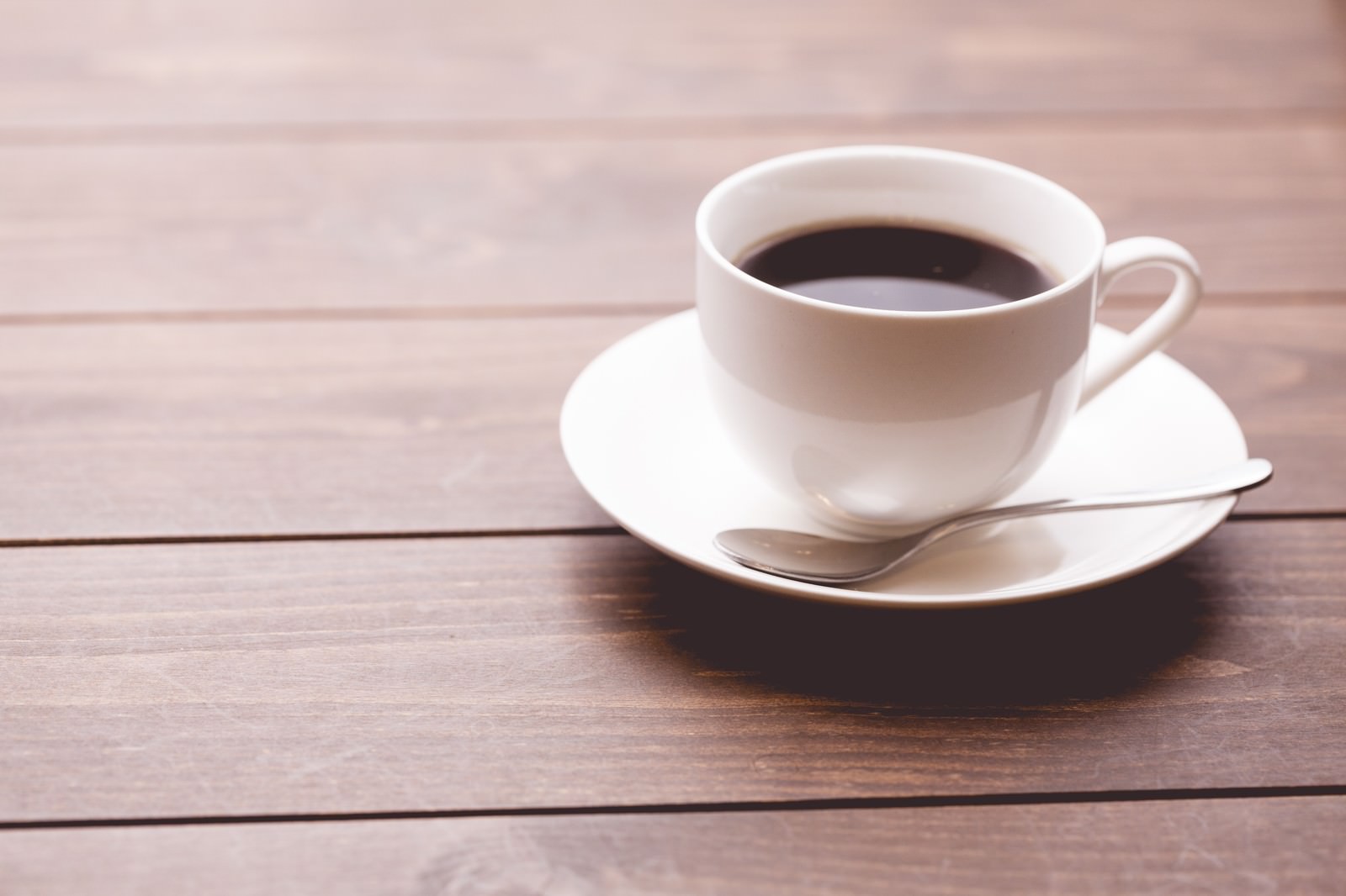 木製テーブルの上の白いカップのコーヒー