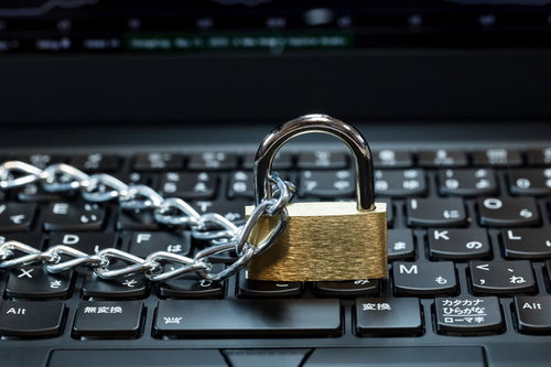 ノートパソコンのキーボードの上に置かれた南京錠と鎖