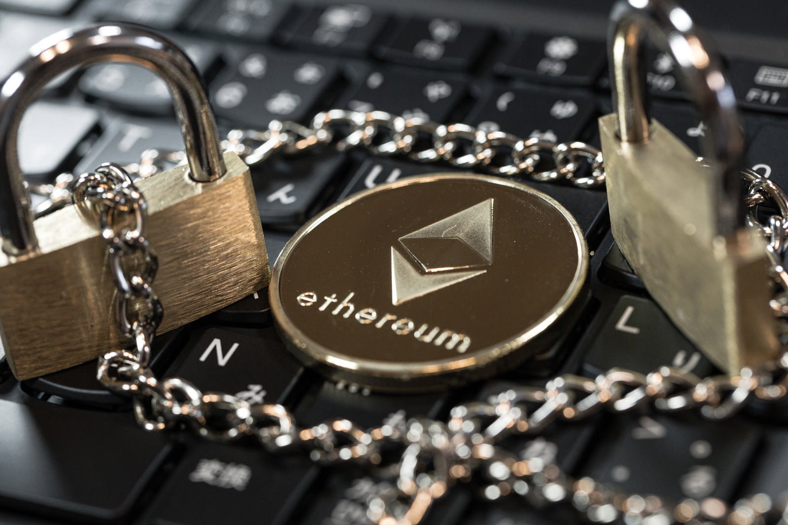 イーサリアムのロゴが刻まれた金色の南京錠と金属チェーン