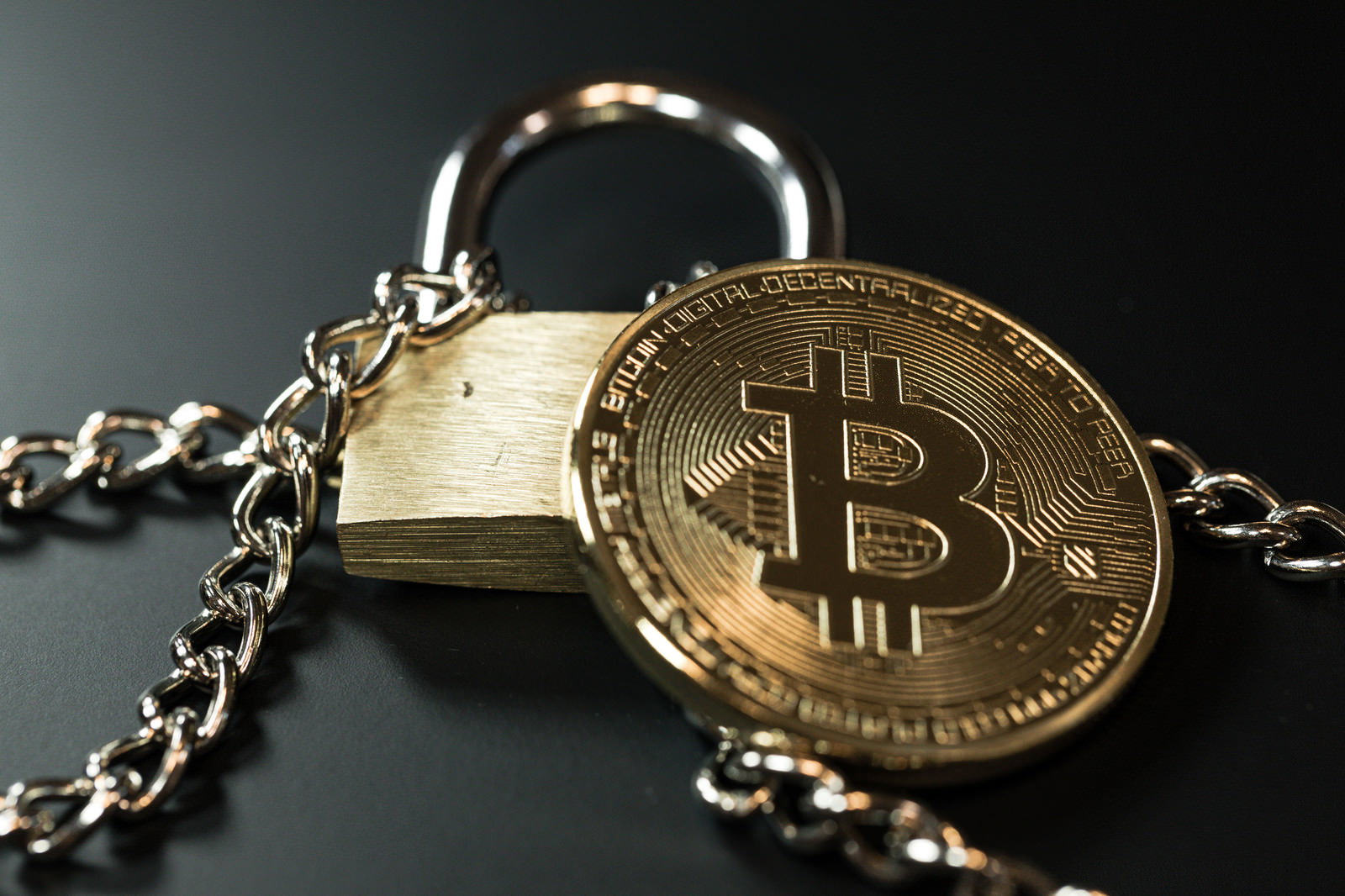 チェーンで繋がれた南京錠とビットコインコインのセキュリティイメージ