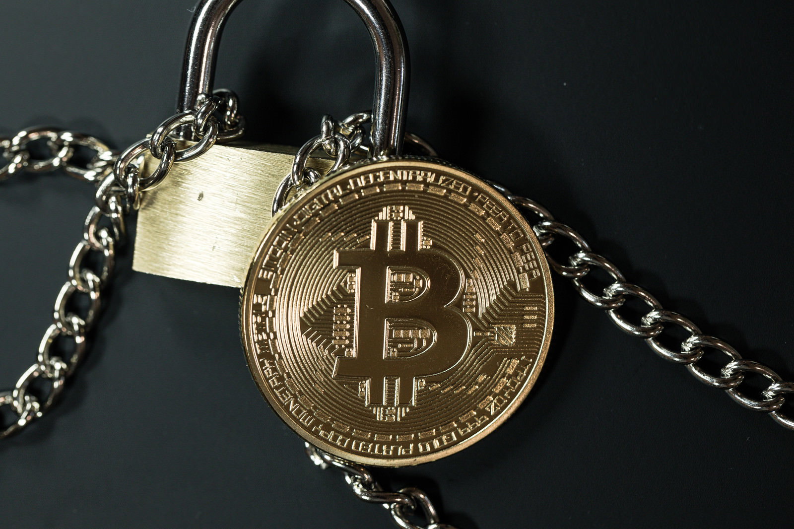 南京錠と鎖で固定された金色のビットコインコイン