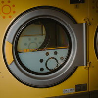 コインランドリーの黄色いドラム式洗濯機と操作パネルの写真