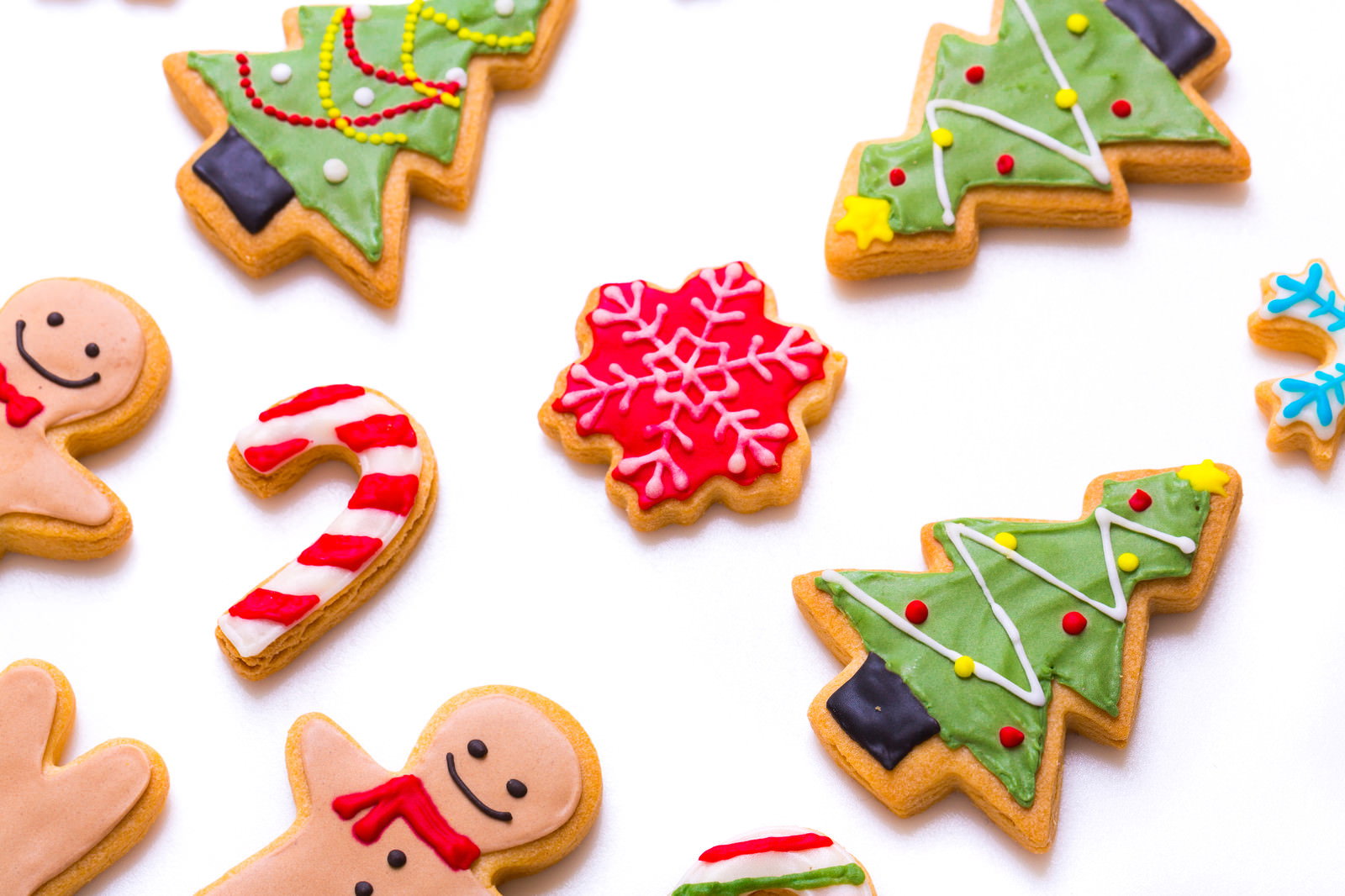 白い背景に散らして配置されたクリスマス柄のアイシングクッキー